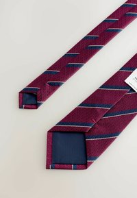 Burgundy tie featuring a textured pattern, with diagonal navy stripes and white accents. Flat, pointed ends with a solid navy lining.