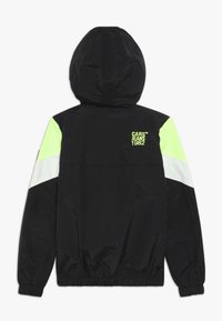 Černá bunda s kapucí s neonově zelenými a bílými akcenty na ramenou. Obsahuje značkový nápis a elastické manžety a lem. Hladká textura.