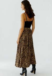 Maxi rok met luipaardprint gemaakt van een zachte stof, met een geplooid ontwerp en een elastische tailleband, gecombineerd met zwarte enkellaarsjes.