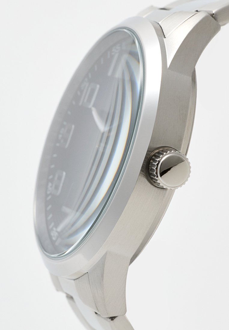 Reloj de acero inoxidable con esfera circular, esfera gris y detalles en plata. Cuenta con una corona texturizada y vidrio transparente para una buena visibilidad.