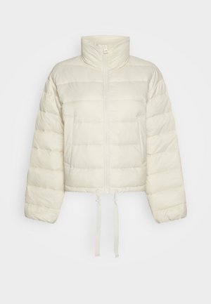 Zkrácená péřová bunda světlé krémové barvy, s vysokým límcem, předním zipem, dvěma kapsami a nastavitelné šňůrce na lemu.