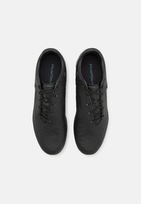 Zwarte sportschoenen met een gestructureerd oppervlak, voorzien van ronde patronen, veters en een comfortabele, gevoerde inlegzool met zichtbare "PHANTOM" branding.