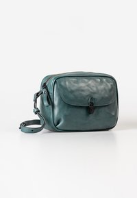 Borsa a tracolla in pelle teal con pattina anteriore, chiusura con zip e tracolla regolabile. Presenta una superficie liscia e dettagli di cucitura discreti.