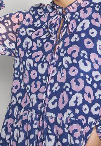 Blå och rosa leopardmönstrad klänning med krage, nyckelhålsdetalj, långärmar och volangkjol. Lätt, texturerad tyg.
