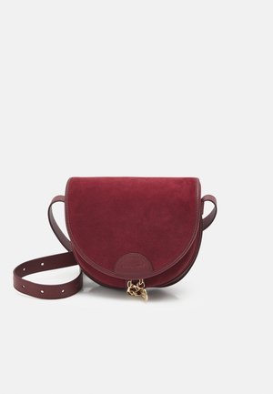Kleine afgeronde bordeaux suède crossbodytas met verstelbare band en goudkleurig bedeltje op de klepsluiting.
