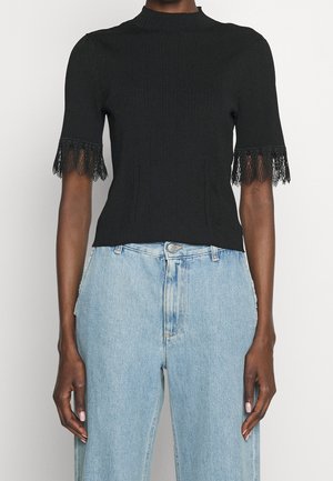 Haut noir côtelé à manches courtes avec bordure en dentelle sur les manches, porté avec un jean en denim bleu clair taille haute.