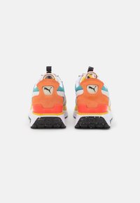 Baskets Puma au design multicolore. Les caractéristiques incluent une base blanche, un talon orange, une semelle de traction noire, ainsi que des accents teal et jaunes.