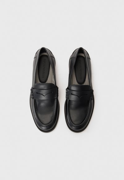 Svarta läderloafers med en slät yta, med ett dekorativt band och subtila sömmar. Texturerad innersula med synligt varumärke.
