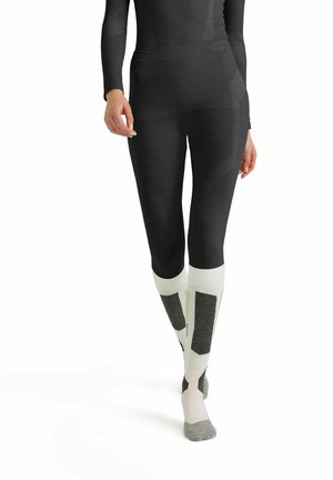 Zwarte thermoleggings met een gestructureerd ontwerp, gecombineerd met kniehoge witte sokken met grijze en zwarte accenten. Glad, aansluitend model.