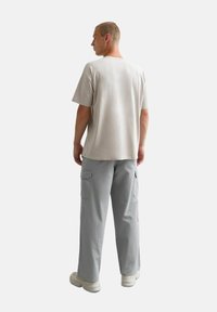 Lichtgrijs T-shirt met een ontspannen pasvorm, korte mouwen, gecombineerd met lichtgrijze cargobroek met zijzakken en een losse silhoeèt.
