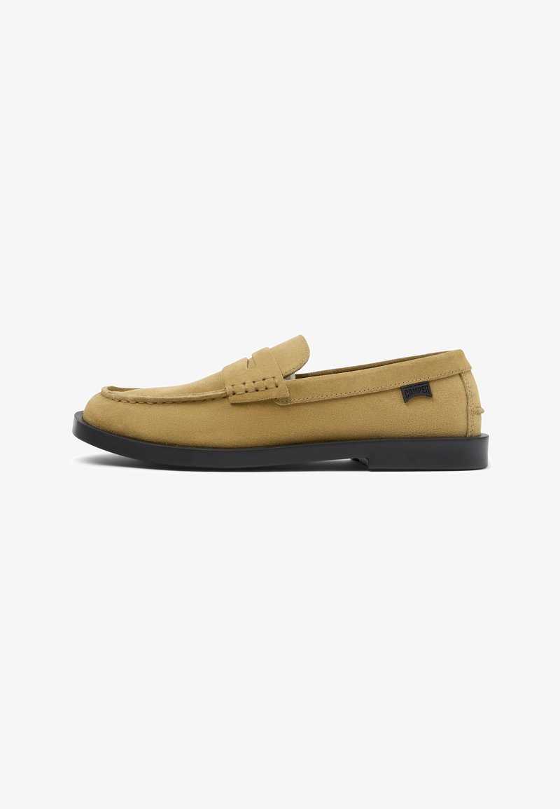 Mocassins en daim jaune à bout arrondi, avec un détail cousu sur le dessus et une semelle en caoutchouc noire. Petite étiquette logo sur le côté.
