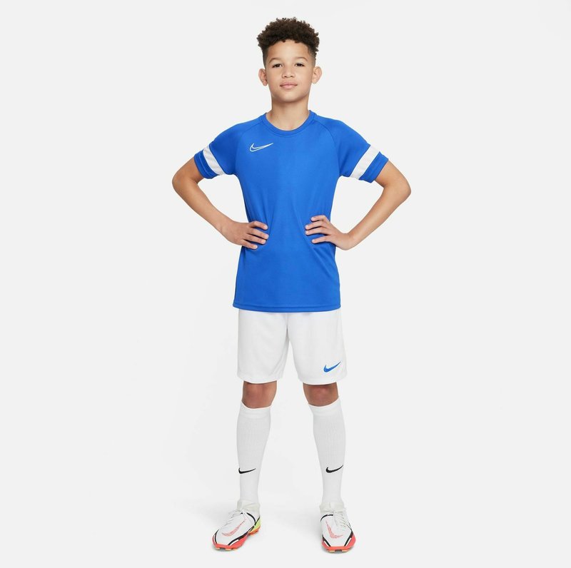 Maillot de sport bleu avec des rayures blanches, associé à un short blanc, des chaussettes blanches jusqu'aux genoux et des chaussures de football multicolores. Logos Nike présents.