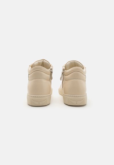 Beige high-top sneakers with smooth leather exterior, padded collar, and side zippers. Textured rubber sole with logo on the heel.