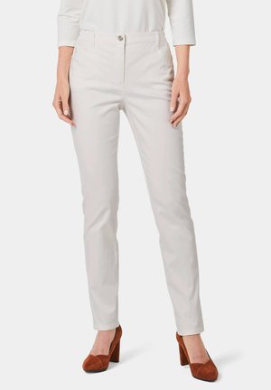 Light beige tailored pants with front pockets and a zip fly, paired with brown suede high-heeled shoes. Smooth texture, slim fit design.