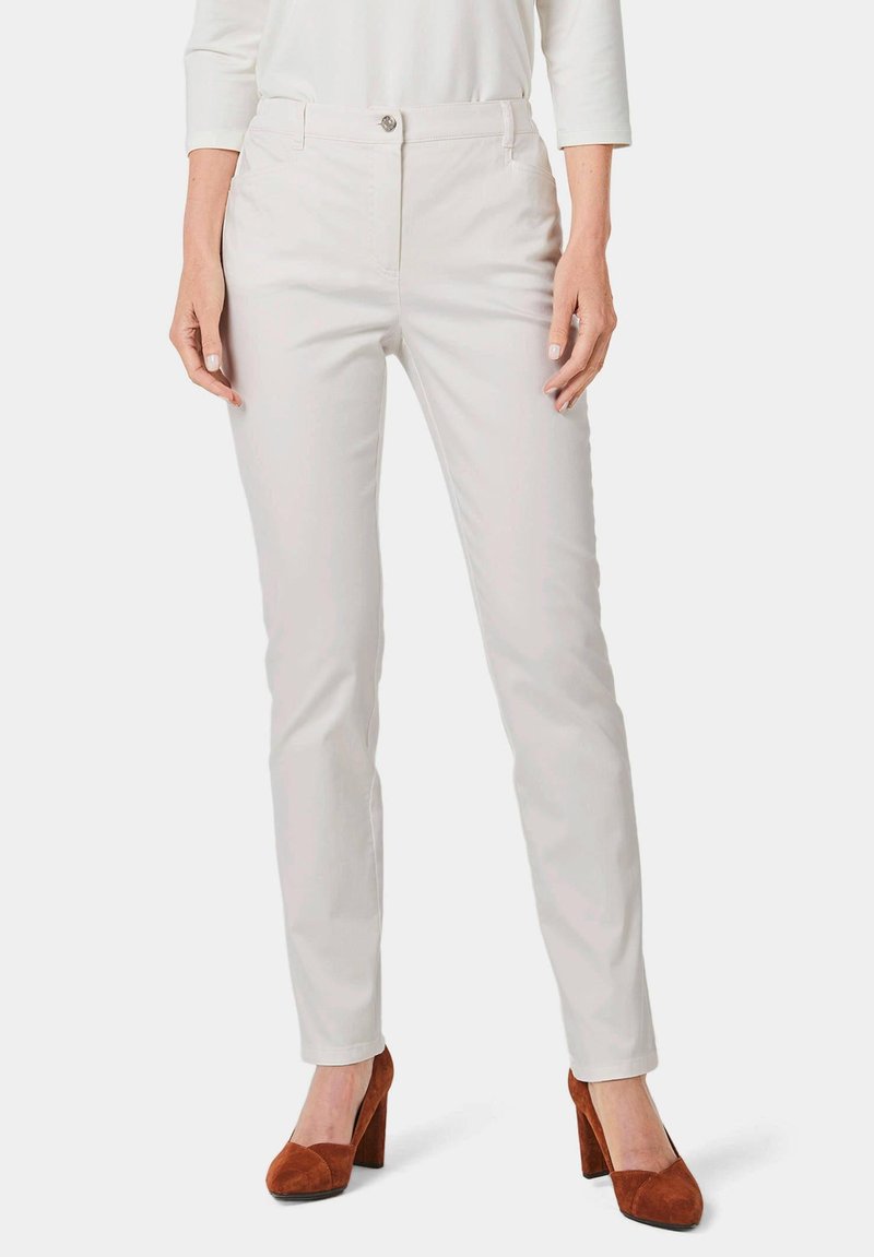 Lichtbeige tailorpantalon met vo pockets en een rits, gecombineerd met bruine suède hoge hakken. Soepele textuur, slim fit ontwerp.