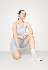 Ljusblått träningsset bestående av en linne med rosa remmar och logotyp, tillsammans med matchande shorts. Vita ankelstrumpor och pastellfärgade sneakers.