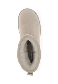 Botín de ante beige con un suave forro de piel de borrego y una suela de goma texturizada, que cuenta con una lengüeta para ponerlo fácilmente.