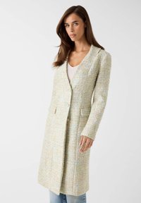 Getextureerde lange jas in pasteltinten, met een diepe V-hals, twee zakken aan de voorkant en twee knopen. Gemaakt van geweven stof met een lichte glans.