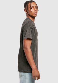 Grå kortærmet t-shirt med rund hals, lavet af blødt stof, der har et subtilt grafisk print på forsiden og en afslappet pasform.
