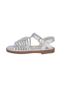 Sandalia metálica plateada con diseño de punta abierta, múltiples tiras, un hebilla ajustable en el tobillo y suela plana marrón.