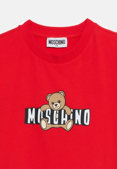 Κόκκινο παιδικό t-shirt Moschino με ριμπ λαιμόκοψη, που διαθέτει γραφικό ενός καφέ αρκουδάκι πάνω σε λευκό και μαύρο κείμενο "MOSCHINO".