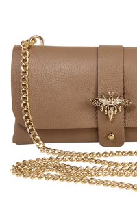 Bruine leren clutch met een gouden kettingriem, voorzien van een decoratief bijenembleem en een klep sluiting. Het oppervlak heeft een gestructureerde afwerking.