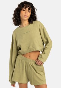 Felpa corta verde chiaro con maniche lunghe e una texture semplice, abbinata a pantaloni corti coordinati con una vita elastica.