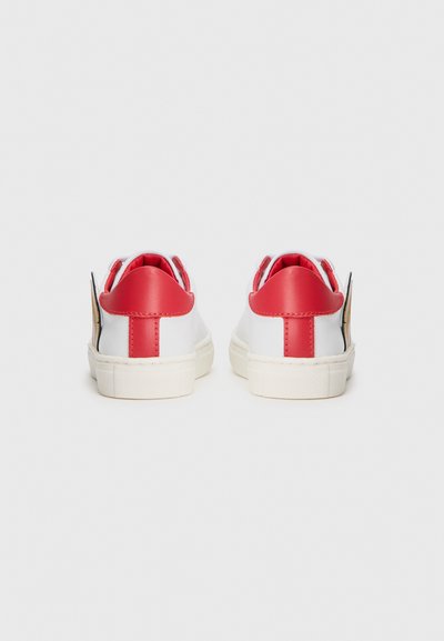 Vita sneakers med röda accenter vid hälen och tungan. Slät läderöverdel, texturerad gummisula och en liten etikett på sidan.