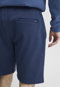 Námorné modré šortky vyrobené z mäkkej tkaniny, s elastickým pásom, bočnými vreckami a jedným zadným vreckom s malou nášivkou.
