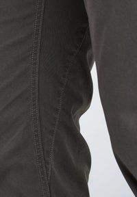 Dunkelgraue Hose aus strukturiertem Stoff, Slim Fit und mit kontrastierenden Nähten entlang der Seitennaht.