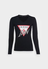 Černé dlouhé rukávy tričko s výstřihem do V vyrobené z bavlny, s červenou trojúhelníkovou grafikou se stříbrným nápisem "GUESS" a "ICON" a třpytkami.