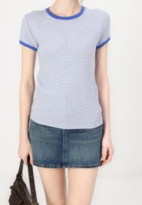 T-shirt rayé bleu et blanc à manches courtes et col côtelé bleu, associé à une mini-jupe en denim. Design simple et ajusté.
