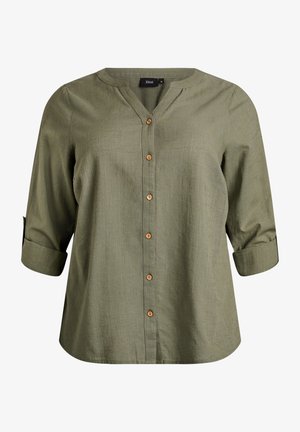 Oliveiroheline nööbitav särk V-kaelusega, kolmveerandvarrukatega ja puidust nööpidega. Valmistatud tekstuurse kangaga, lõdva istuvusega.