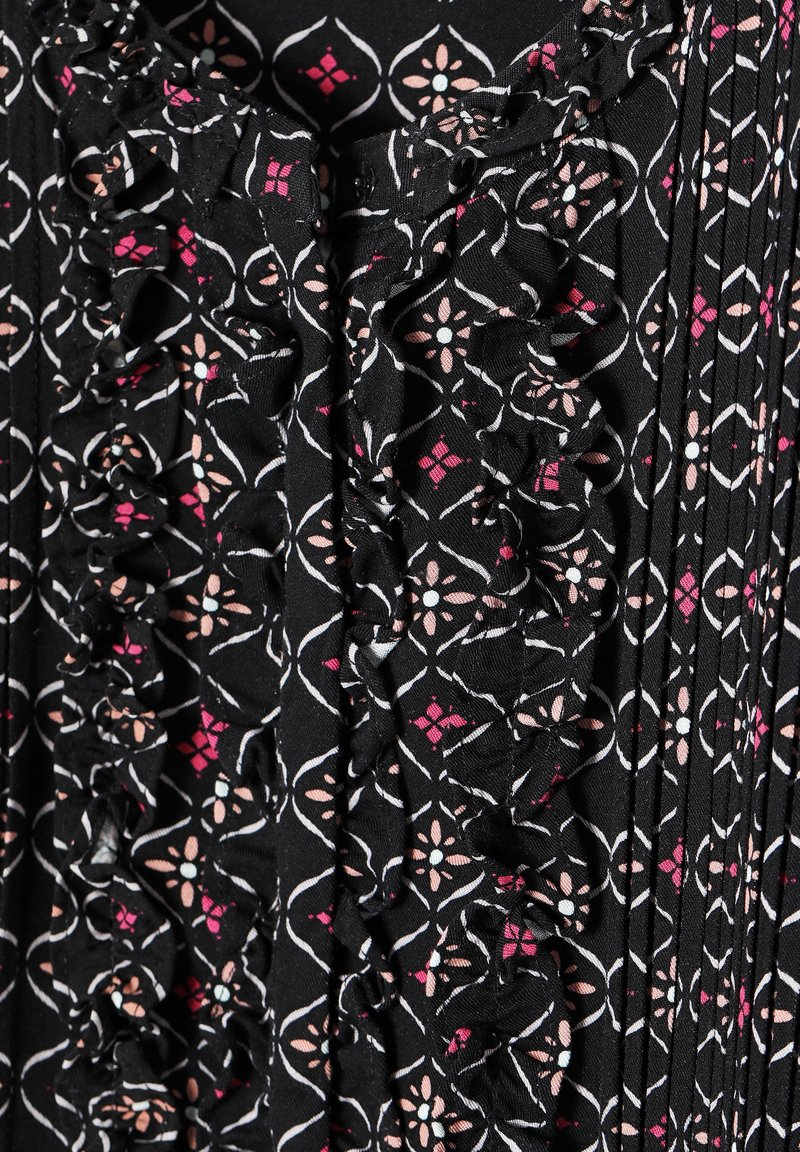 Czarna tkanina w kwiatowe i diamentowe wzory w odcieniach różu i bieli, z falbanami wzdłuż szwu oraz pionowymi plisami na całej powierzchni.