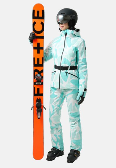 Strój narciarski w miętowym wzorze w kamuflażu, gogle śnieżne, czarny kask i pomarańczowy snowboard z czarnym napisem. Teksturowany materiał i dopasowany krój.