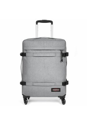 Gray wheeled suitcase with a textured finish, extendable handle, front zip pocket, and adjustable straps. Features four wheels for mobility.