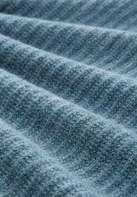Niebieska tkanina o teksturowanym, miękkim wzorze o splocie. Charakteryzuje się wypukłymi paskami i lekko puszystą fakturą, co świadczy o jej ciepłocie i wygodzie.