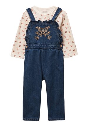 Chemise longue crème à manches longues avec de petites fleurs rouges, associée à une salopette en denim bleu ornée de broderies florales sur la poitrine et de bretelles à volants.