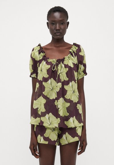 Completo di top a maniche corte e pantaloni corti in viola scuro con una grande stampa floreale verde. Tessuto leggero, scollatura elastica e vestibilità comoda.