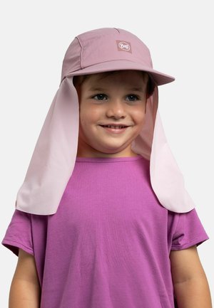 Niño con una gorra rosa de protección solar con faldón en el cuello y camiseta de manga corta morada, sonriendo, sobre un fondo liso y claro.