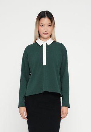 Dark green long-sleeve polo top featuring a white collared neckline and button placket, made from soft fabric with a relaxed fit.