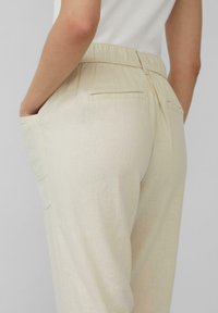 Lichtbeige linnen broek met een elastische tailleband, zijzakken en een gladde textuur, van achter te zien zonder zichtbare patronen.