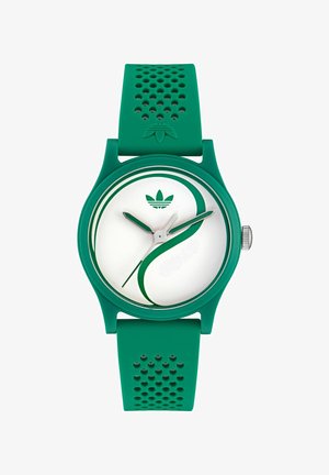 Montre en silicone verte avec un cadran blanc rond, dotée d'un design courbé vert, des aiguilles argentées, et un bracelet texturé vert avec des perforations.