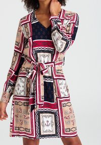 Mehrfarbiges Kleid mit V-Ausschnitt, langen Ärmeln, einem Taillengürtel und einem Muster aus Ketten und Rahmen in Beige, Marineblau, Rot und Weiß.