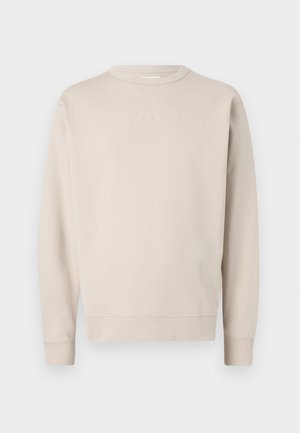 Sweatshirt beige en tissu doux avec des manches longues, un col ras du cou et des poignets côtes. Présente un discret détail de couture au niveau du cou.