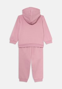 Roze hoodie en sweatpants set gemaakt van zachte stof. De hoodie heeft een trekkoord en ribgebreide manchetten; de broek heeft een elastische tailleband en manchetten.