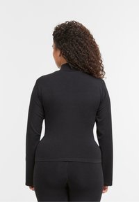 Top negru cu mâneci lungi, realizat dintr-un material elastic, având un guler înalt și un design ajustat. Textură netedă, linii simple și curate.