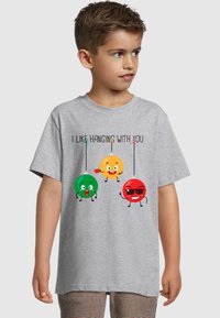 Grå bomuld t-shirt med korte ærmer, der viser tre tegneserie-frugtfigurer i grøn, gul og rød med teksten "JEG KAN GODT LIDE AT HÆNGE UD MED DIG."
