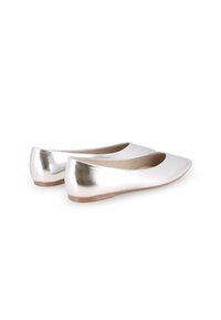 Bailarinas metálicas plateadas con punta afilada, superficie lisa y diseño minimalista. Presentan un tacón bajo y un forro interior suave de color beige.