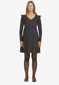 Schwarzes, langärmliges Kleid mit Rüschen an den Schultern, V-Ausschnitt und Knopfdetails an der Vorderseite, mit einem ausgestellten, knielangen Schnitt.